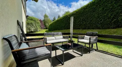a patio with two chairs and a table with a fire place at Studio rénové avec terrasse Sud idéalement situé in Combloux