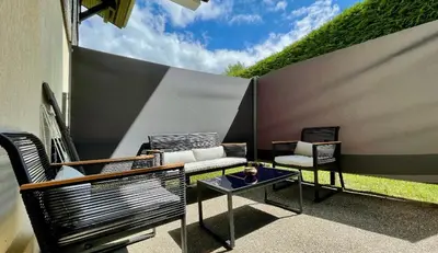 a patio with two chairs and a table and a fence at Studio rénové avec terrasse Sud idéalement situé in Combloux