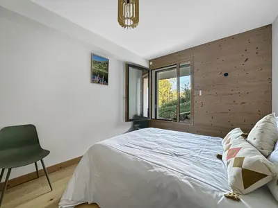 a bedroom with a bed and a chair and a window at GRD005 - Appartement standing 6 pers pied de piste in Les Carroz d'Araches