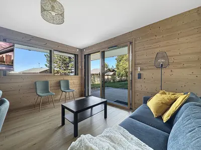 a living room with a blue couch and some windows at GRD005 - Appartement standing 6 pers pied de piste in Les Carroz d'Araches