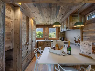 a kitchen with wooden walls and a table with wine bottles at Appartement rénové à 150m des remontées, terrasse et parking couvert - FR-1-569-126 in Megève