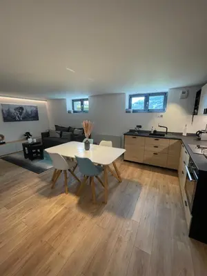 a kitchen and living room with a white table and chairs at Appartement - La Meute in Magland