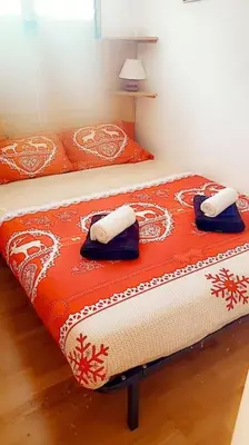 a bed with orange and white sheets and pillows at Appartement montagnard avec vue sur le Mont-Blanc in Saint-Gervais-les-Bains