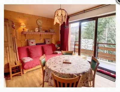a living room with a table and a red couch at Appartement montagnard avec vue sur le Mont-Blanc in Saint-Gervais-les-Bains