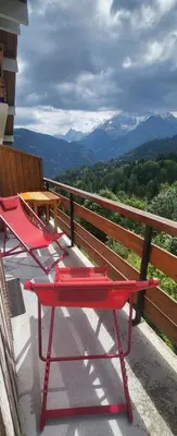 two red picnic tables on a balcony with a view of mountains at Appartement montagnard avec vue sur le Mont-Blanc in Saint-Gervais-les-Bains
