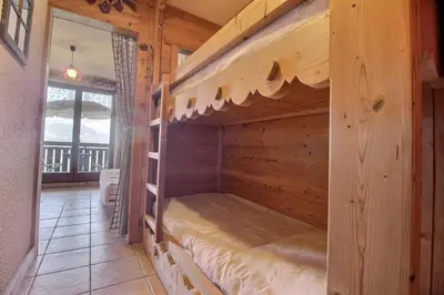 a bunk bed in a wooden cabin with a window at Studio coin nuit style chalet in Saint-Gervais-les-Bains