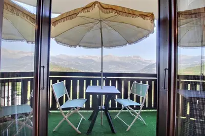 a table and chairs on a balcony with an umbrella at Studio coin nuit style chalet in Saint-Gervais-les-Bains