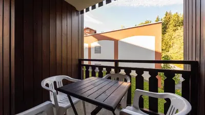 a wooden table and two chairs on a balcony at Grande Neige 23 - Appt pied des pistes 4 pers in Morillon