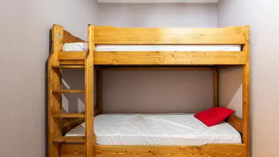 two bunk beds in a room with a red pillow at Grande Neige 23 - Appt pied des pistes 4 pers in Morillon