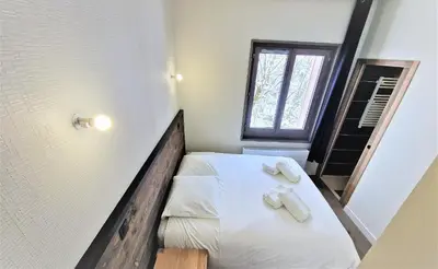 a small bedroom with a bed with white sheets and towels at White Pearl Vue Mont Blanc in Chamonix-Mont-Blanc