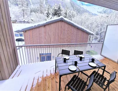 a patio with a table and chairs on a balcony at White Pearl Vue Mont Blanc in Chamonix-Mont-Blanc
