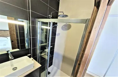 a bathroom with a sink and a glass shower door at White Pearl Vue Mont Blanc in Chamonix-Mont-Blanc