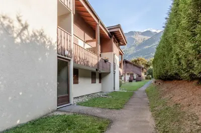 a walkway next to a building with mountains in the background at Sapins 11 - Appartement familial - Pied des pistes - Vue sur les montagnes in Les Houches