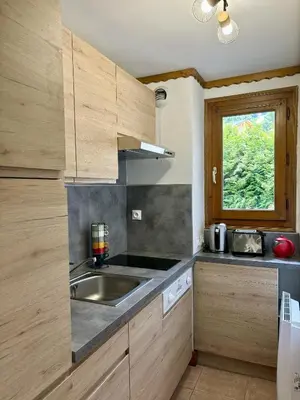 a kitchen with wooden cabinets and a sink and a window at Sapins 11 - Appartement familial - Pied des pistes - Vue sur les montagnes in Les Houches