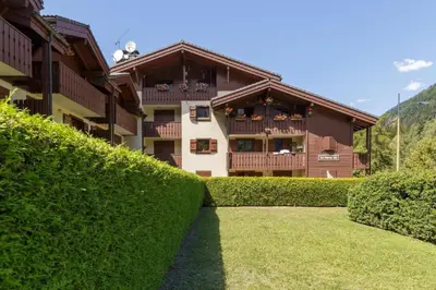 a house with a hedge in front of a building at Sapins 11 - Appartement familial - Pied des pistes - Vue sur les montagnes in Les Houches