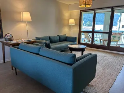 a living room with a blue couch and a table at Appartement 109 in Sallanches