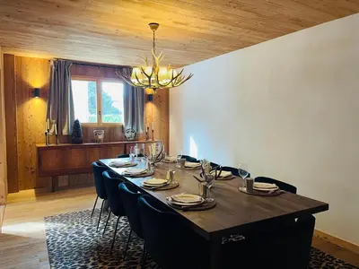 a dining room with a long table with chairs and a chandelier at RED LODGE in Megève
