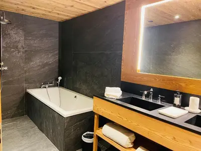 a bathroom with a sink and a bath tub and a mirror at RED LODGE in Megève