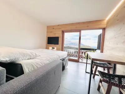 a bedroom with a bed and a table and a window at Appartement 4 personnes pistes in Combloux