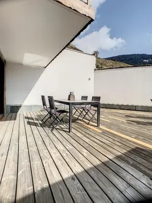 a patio with a table and chairs on a deck at rous 03 in Les Carroz d'Araches