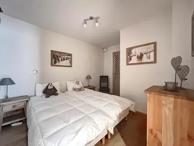a bedroom with a large white bed with a teddy bear on it at rous 03 in Les Carroz d'Araches