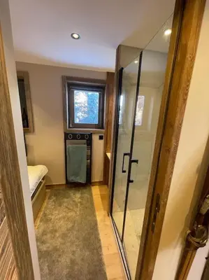 a bathroom with a glass shower and a window at Appartement centre megeve in Megève