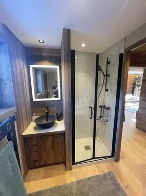 a bathroom with a sink and a glass shower at Appartement centre megeve in Megève