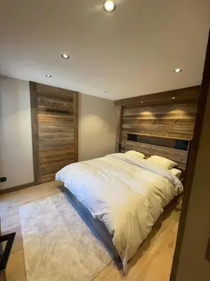 a bedroom with a large bed with a wooden headboard at Appartement centre megeve in Megève