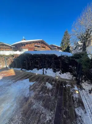 a yard covered in snow with a fence at Appartement centre megeve in Megève