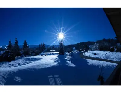 a sun shining in the sky over a snow covered field at Modern 2 bedroom apartment, close to ski lifts in Megève