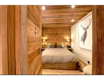 a bedroom with a bed in a room with wooden walls at Modern 2 bedroom apartment, close to ski lifts in Megève