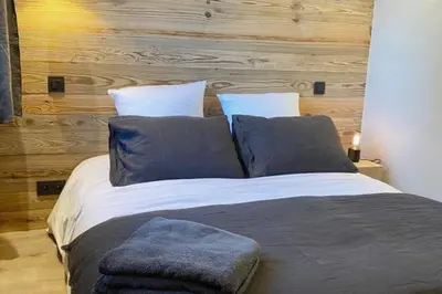 a large bed with blue pillows in a bedroom at Megeve cosy appartement Bianca centre in Megève