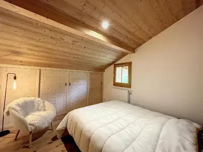 a bedroom with a white bed and a chair at Appartement neuf avec vue Mont Blanc, parking et wifi à Combloux - FR-1-560-113 in Combloux