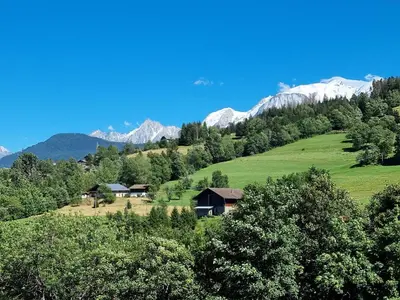 a house on a hill with mountains in the background at Appartement neuf avec vue Mont Blanc, parking et wifi à Combloux - FR-1-560-113 in Combloux
