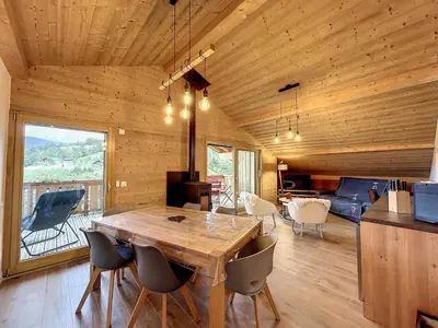 a dining room with a large wooden table and chairs at Appartement neuf avec vue Mont Blanc, parking et wifi à Combloux - FR-1-560-113 in Combloux