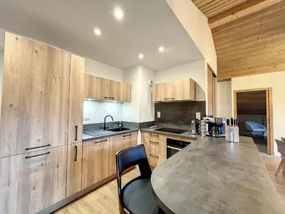 a kitchen with wooden cabinets and a table and chairs at Appartement neuf avec vue Mont Blanc, parking et wifi à Combloux - FR-1-560-113 in Combloux