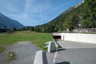 a bridge over a road with a field and mountains at SmartStay Mummery - Chamonix in Chamonix-Mont-Blanc