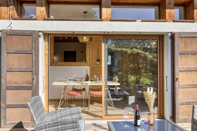 a house with sliding glass doors with a table and chairs at chalet Relax située a 25km de Chamonix in Saint-Gervais-les-Bains