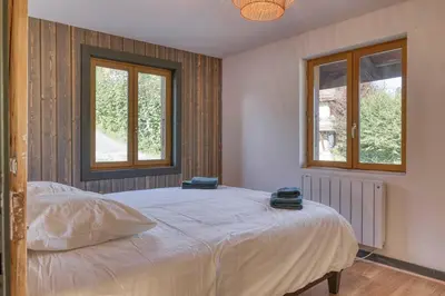 a bedroom with a large bed with two windows at Appartement «Chez Paulette»situé à 25Km chamonix  in Saint-Gervais-les-Bains