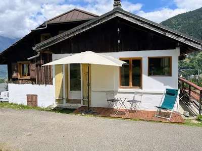 a house with chairs and an umbrella in front of it at Appartement «Chez Paulette»situé à 25Km chamonix  in Saint-Gervais-les-Bains