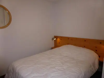 a small bedroom with a white bed with a wooden headboard at Résidence Les Trolles - Trolles 5A MAE-7374 in Les Contamines-Montjoie