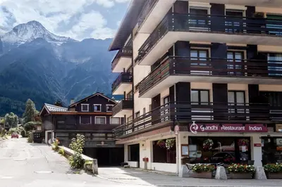 a building with balconies on it with mountains in the background at Les Marmottes - Renovated and cozy apart - View of the mountains in Les Houches