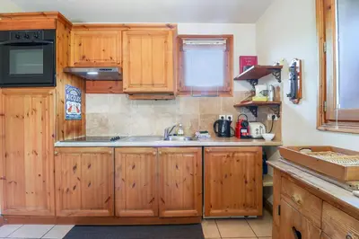 a kitchen with wooden cabinets and a sink at Amethyste - 2 Bedrooms & Free Parking - By Cozee Rentals in Les Houches
