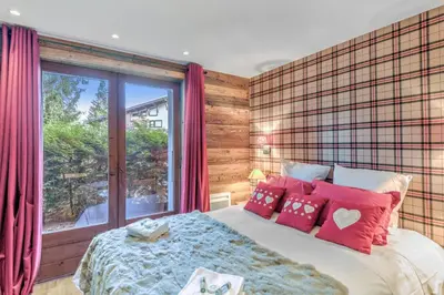 a bedroom with a bed with red pillows and a window at Le Chalet Vigas - Welkeys in Megève