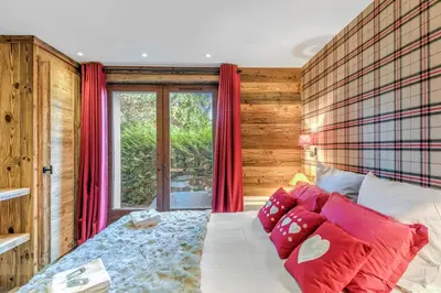 a bedroom with a bed with red curtains and a window at Le Chalet Vigas - Welkeys in Megève