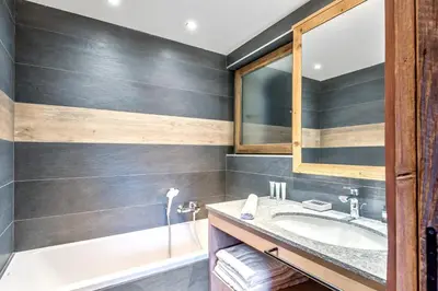 a bathroom with a sink and a tub at Le Chalet Vigas - Welkeys in Megève