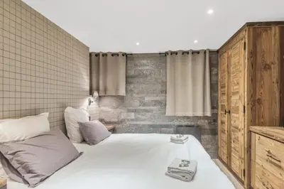 a bedroom with a white bed and a brick wall at Le Chalet Vigas - Welkeys in Megève