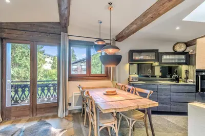 a kitchen and dining room with a wooden table and chairs at Le Chalet Vigas - Welkeys in Megève