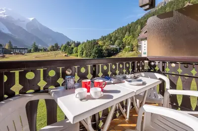 a table on a balcony with a view of a mountain at Family Apartment Mont Blanc View in Chamonix-Mont-Blanc