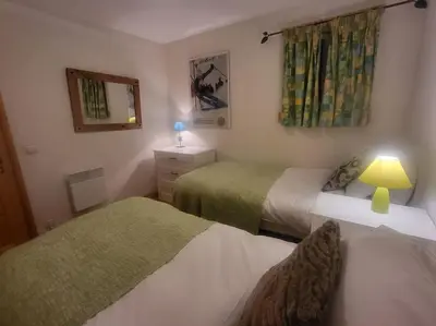 a bedroom with two beds and a lamp and a mirror at A1/2, 3 bedroom apartment next to the ski lift in Samoëns